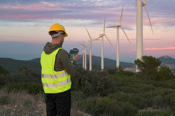 istock Man working at a wind farm directs a drone at sunset 1447899879