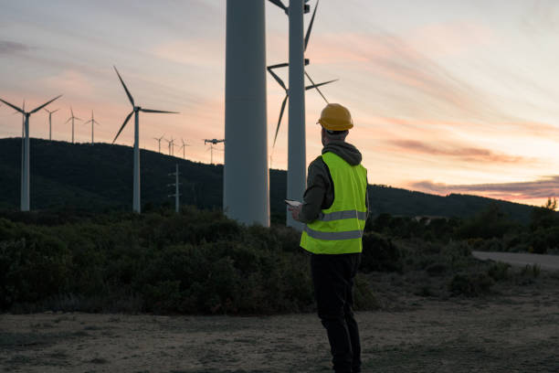 istock Man working at a wind farm directs a drone at sunset 1447899888