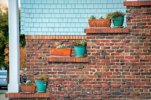 Outside brick exterior with decorative blue or geen pots for plants and square adobe containes with white pillar and wooden pannels. In shade in the late afternoon in suburban areas downtown.