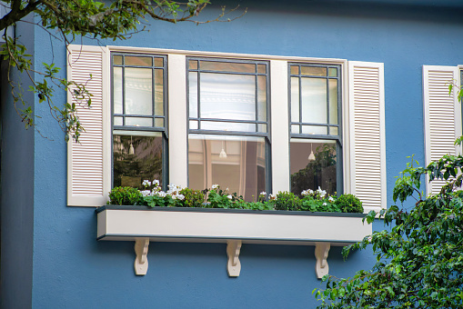 Modern building with decorative blue stucco exterior with white shutters and balcony with accent paint on house or home. In the historic districts of downtown san francisco california in the streets.