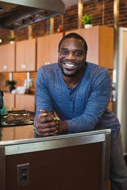 istock Charming Black man leaning against the kitchen counter, smiling and contemplating 1447903612