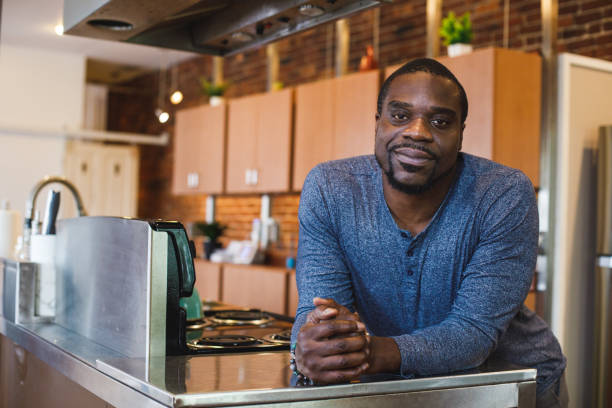 istock Charming Black man leaning against the kitchen counter, smiling and contemplating 1447903617