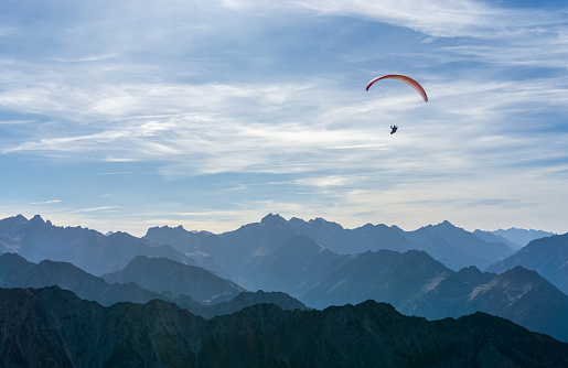 Paragliding above blue Mountains Silhouette, Allgaeu, Oberstdorf, Alps, Germany. Travel destination. Summer and holiday concept.
