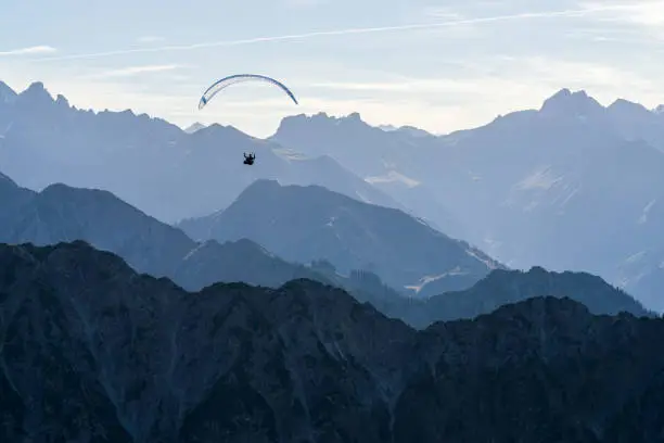 Paragliding above blue Mountains Silhouette, Allgaeu, Oberstdorf, Alps, Germany. Travel destination. Summer and holiday concept.