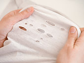 A woman stretching a shirt with holes