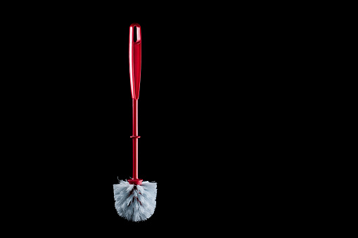 Separate brush to clean the toilet with a red handle on a black background, isolate
