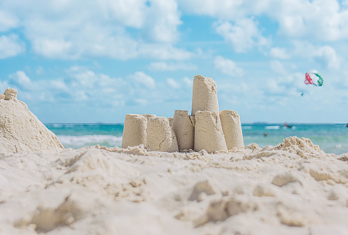 Adorable little boy playing on beach, building sand castle.