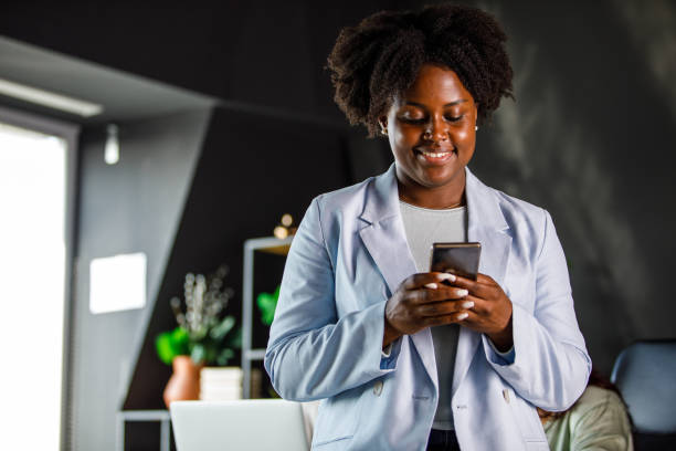 istock Young Black woman typing a text message via smart phone at the office during work break 1447922219