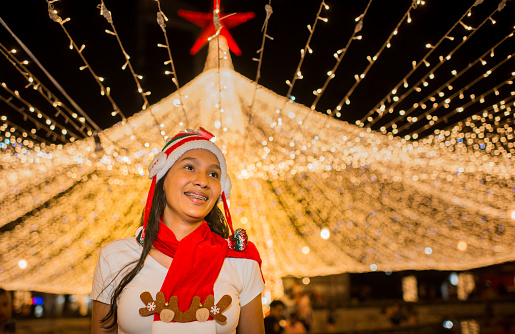 woman in christmas festivities wearing a hat and scarf while enjoying the lighting