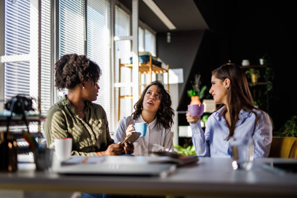 istock Three diverse young women sitting at table, enjoying coffee and chatting 1447924416