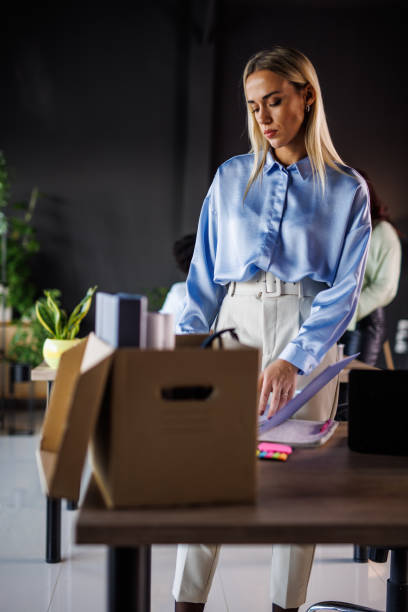 istock Young businesswoman standing over her desk and packing after getting fired 1447925030