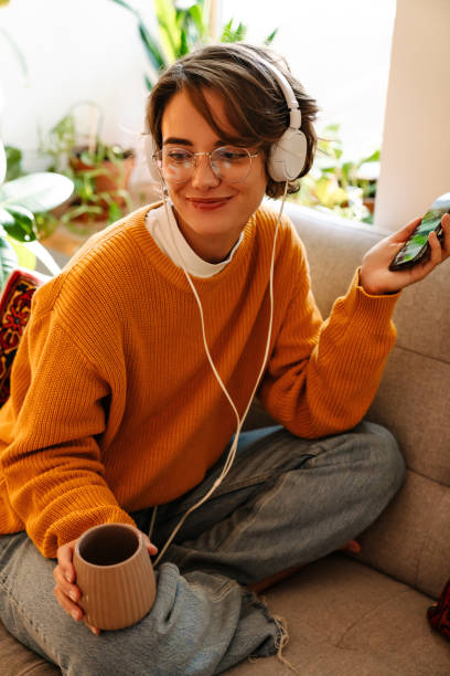 istock Young woman listening music and using cellphone while drinking coffee 1447934936