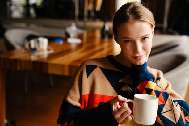 istock Smiling woman drinking tea and looking at camera while sitting in cafe 1447940872