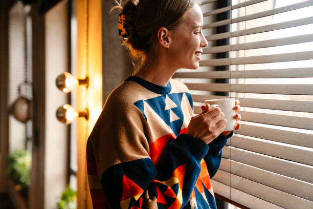 istock Young woman looking out of window while drinking coffee in cafe 1447941033