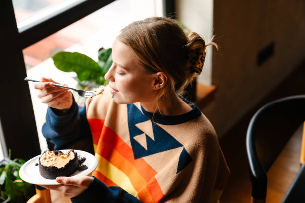 istock Young woman eating dessert while sitting at table in cafe 1447941095