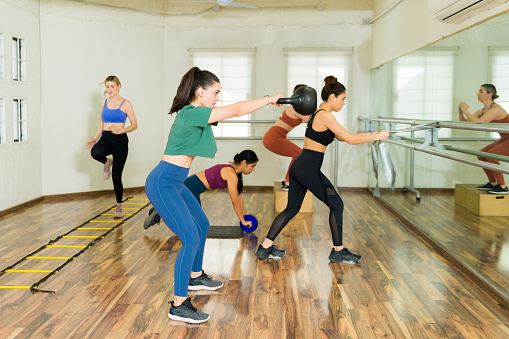 Group of women working out with a kettlebell weight during a high intensity interval training at the fitness studio