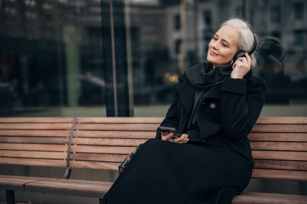 istock Senior woman using phone and sitting on a bench 1447943234