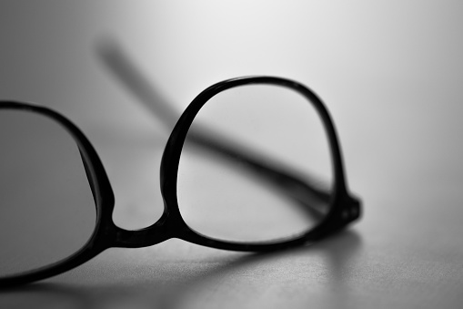 Modern glasses lie on the table against the light. dark mood. copy space