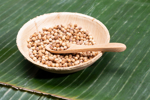 Coriander seeds in a bamboo bowl on banana leaf. High quality photo