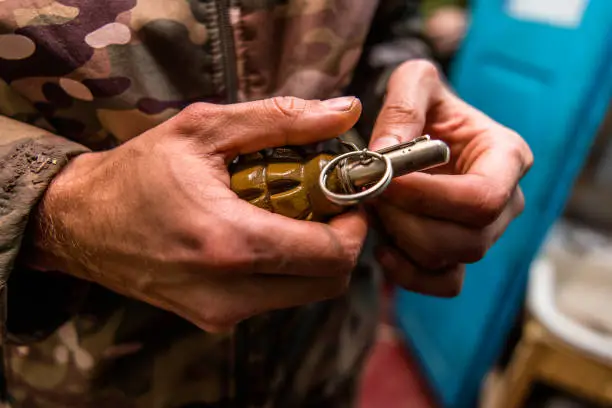 a grenade in a man's hand. Military man holding explosives