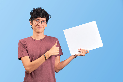 Happy young man showing a placard or advertisement on flat lay.