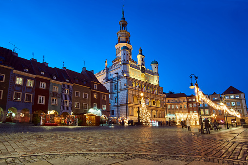 historic tenement houses and the renaissance town hall with Christmas decorations on the market square at night in Poznan