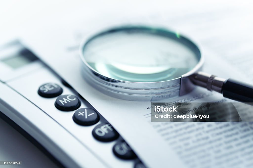 Magnifying glass, calculator on paper Analyzing Stock Photo