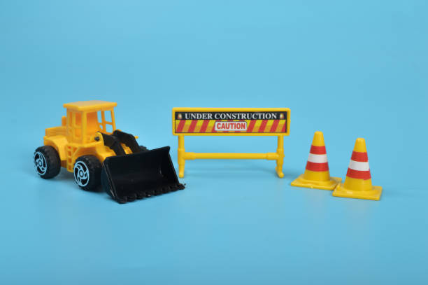 istock Yellow backhoe with construction site signs isolated on a blue background. Danger under construction concept. 1447950224