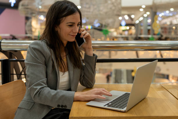 istock Businesswoman using netbook and speaking on cellphone 1447950812