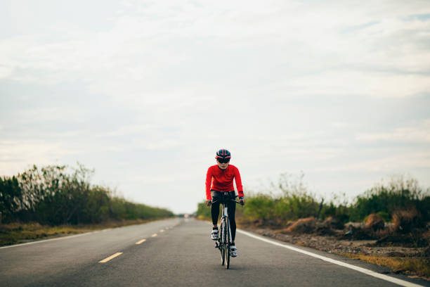 триатлонистка на велосипеде по проселочной дороге - cycling bicycle triathlon women стоковые фото и изображения