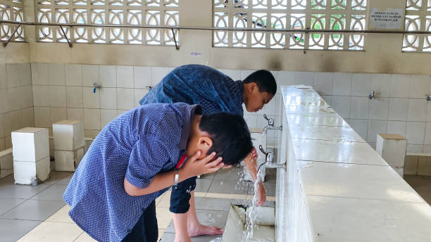 Child Muslim takes ablution for prayer. Islamic religious rite of body cleansing ceremony before prayers