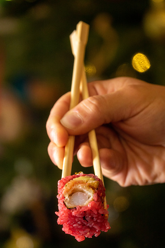 Sushi with hand holding with chopsticks sushi on christmas background
