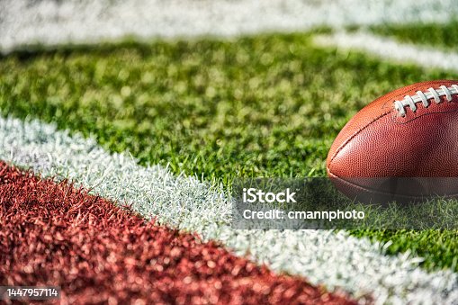 istock A low angle view of an American football inches from the goal line close to a red end zone. 1447957114