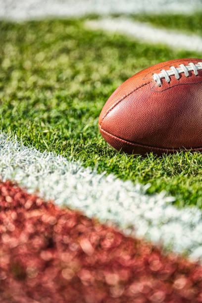 A low angle view of an American football inches from the goal line close to a red end zone. stock photo