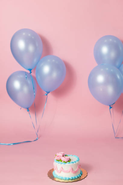 istock A pink backdrop with blue purple lavender balloons for a backdrop birthday celebration with a small birthday cake 1447959030