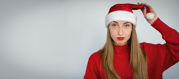 Beautiful blonde girl in a Santa hat and a red sweater. Christmas carnival costume.