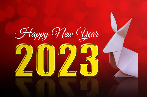 Happy new year 2023 on red background and origami rabbit