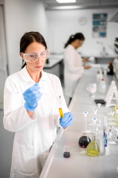 Brown haired female scientist seen using a pipette during some experiment in a laboratory stock photo