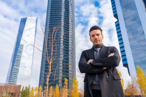 Corporate portrait of middle-aged businessman, business park next to skyscrapers