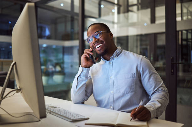 istock Phone call, notebook and computer black businessman at office planning, and writing success strategy for accounting company. South African corporate person work on 5g mobile smartphone, pc and notes 1447961941