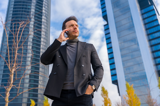 Corporate portrait of Caucasian businessman talking on the phone next to skyscraper office