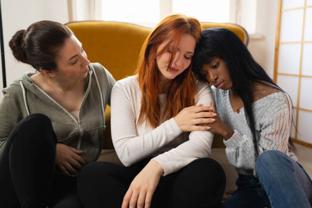 Mixed group of three women comforting a sad friend. Mixed group of three women comforting a sad friend. woman comforting depressed friend stock pictures, royalty-free photos & images