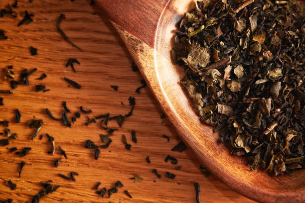istock Flat lay template with scattered tea leaves and wooden spoon on the table 1447964108