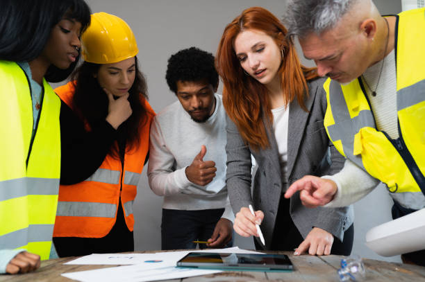 istock Group of five multiracial people working in a construction. Architects examining the project in the office. 1447964248