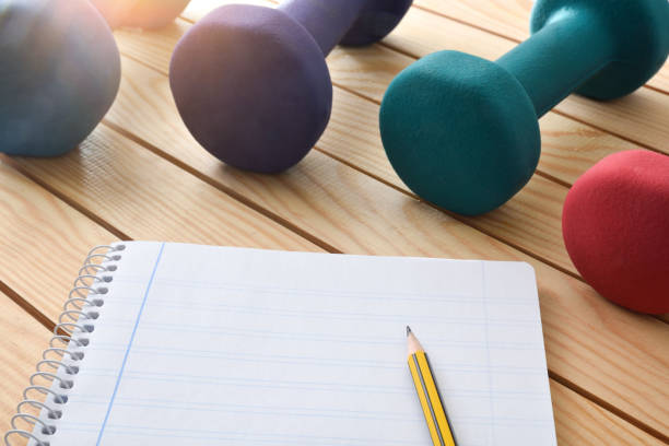 istock Training plan for bodybuilding exercises with notepad and dumbbells 1447964412