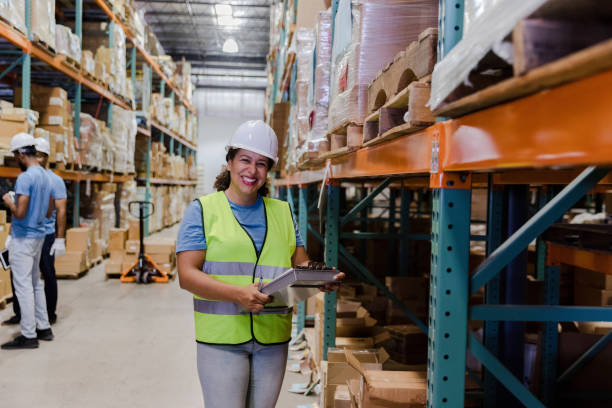 istock Female warehouse manger pauses inventory check to smile for camera 1447965923