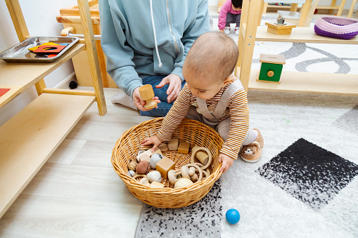 Mother and toddler playing with wooden and felt montessori toys in basket