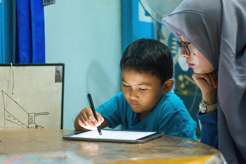 Little boy and older sister using tablet phone doing homework