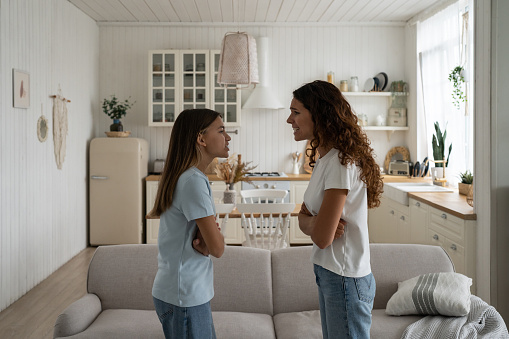 Emotional stepmom and teen stepdaughter. Naughty adolescent girl arguing with mother at home, being rude with parent. Troubled teen child daughter and her mom quarreling, yelling at each other