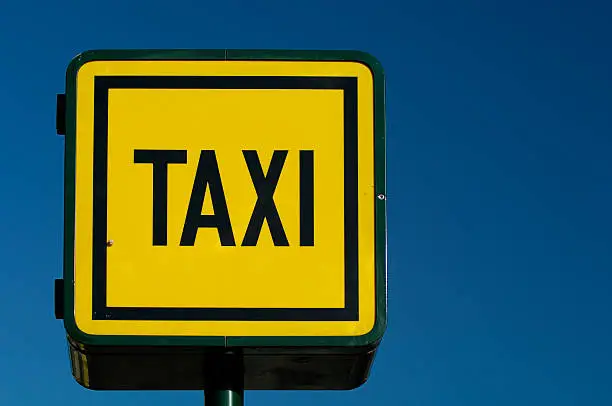 Taxicab stand neon sign with dark blue sky in background